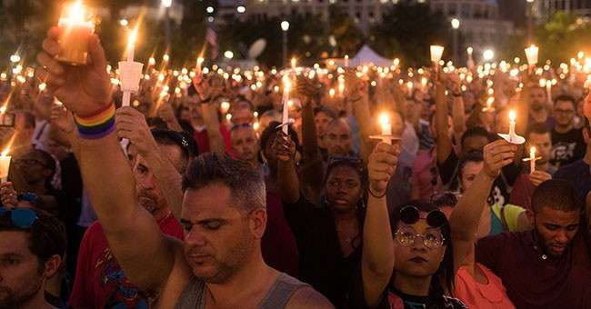 ORLANDO, FL - JUNE 13: People hold candles during an evening memorial service for the victims of the Pulse Nightclub shootings, at the Dr. Phillips Center for the Performing Arts, June 13, 2016 in Orlando, Florida. The shooting at Pulse Nightclub, which killed 49 people and injured 53, is the worst mass-shooting event in American history. (Photo by Drew Angerer/Getty Images)